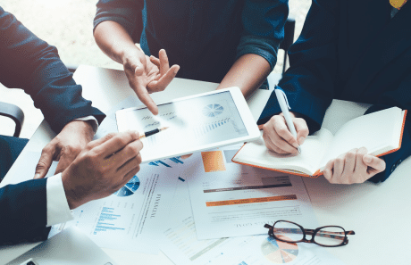 Un gruppo di uomini d'affari seduti attorno a un tavolo con un tablet, discutono delle strategie di Contenuto.