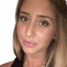 Una donna, parte di una squadra, con i capelli biondi e gli occhi azzurri sta posando per una foto.