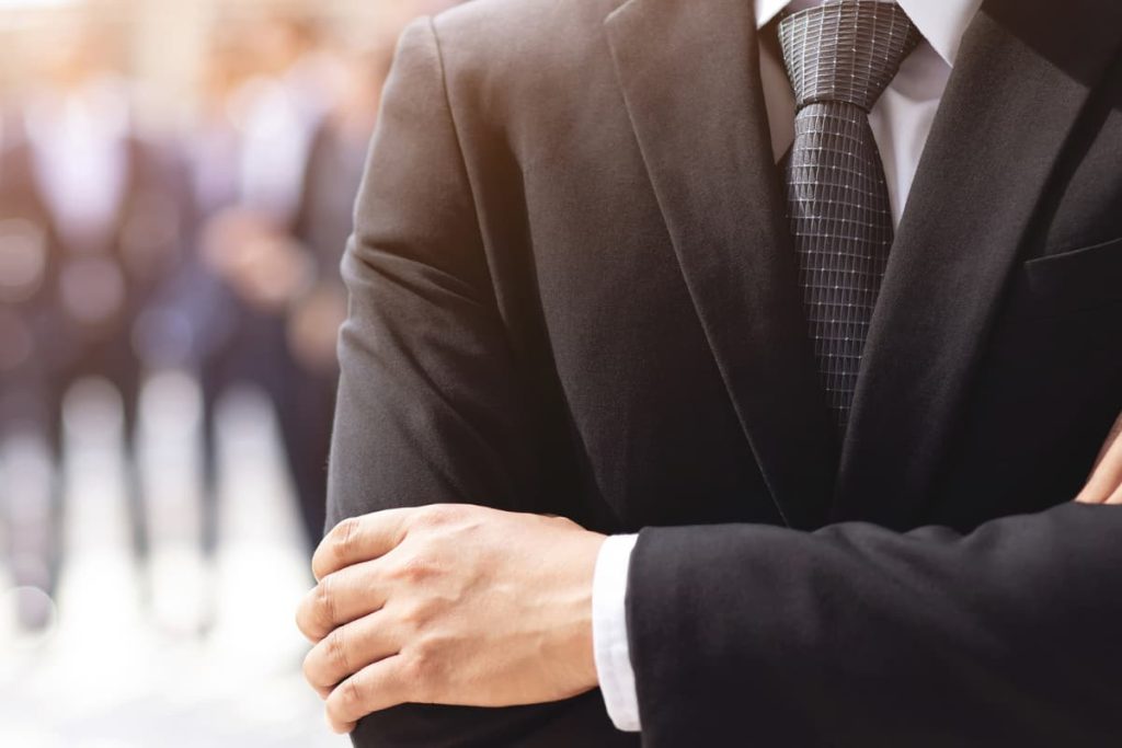 Un uomo d'affari con le braccia incrociate davanti a un gruppo aperto.