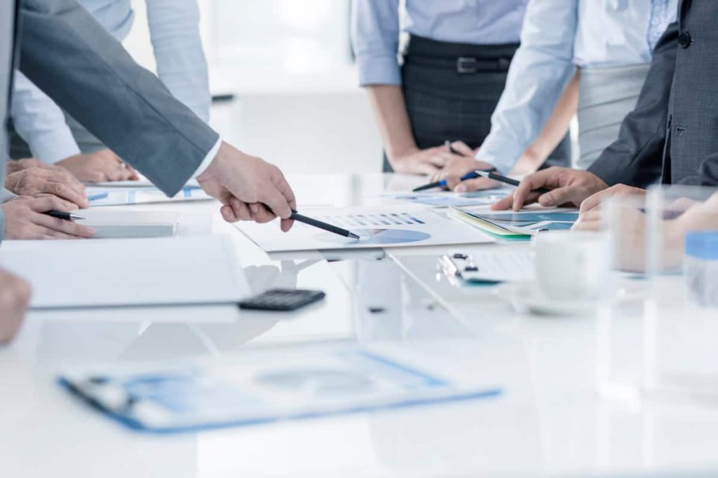 Un gruppo di VECCHI uomini d'affari in piedi attorno a un tavolo.