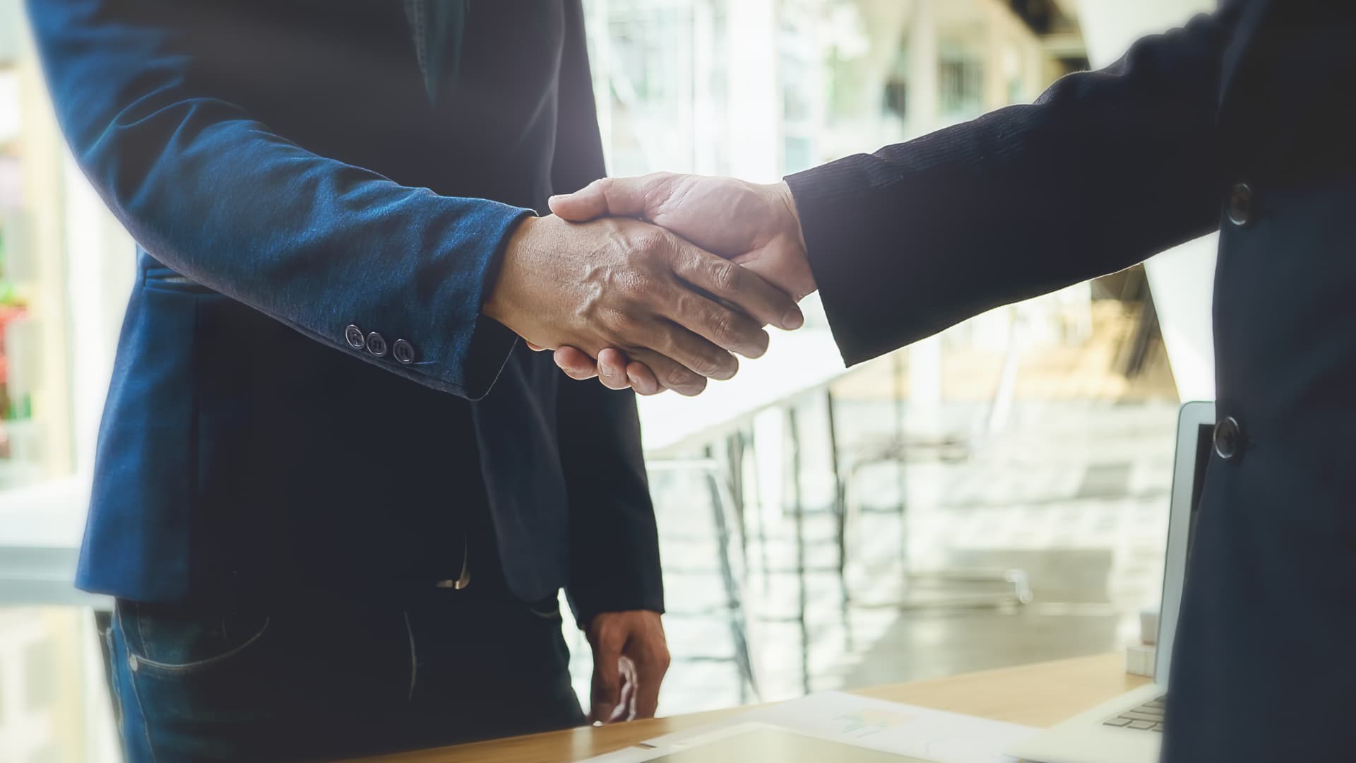 Due uomini d'affari che si scambiano una stretta di mano consultiva alla scrivania.