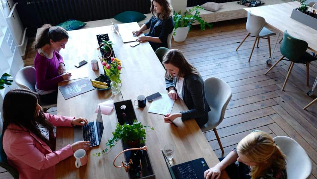 Un gruppo di donne che lavora a un tavolo in un ufficio, concentrandosi sull'assunzione di dipendenti donne.
